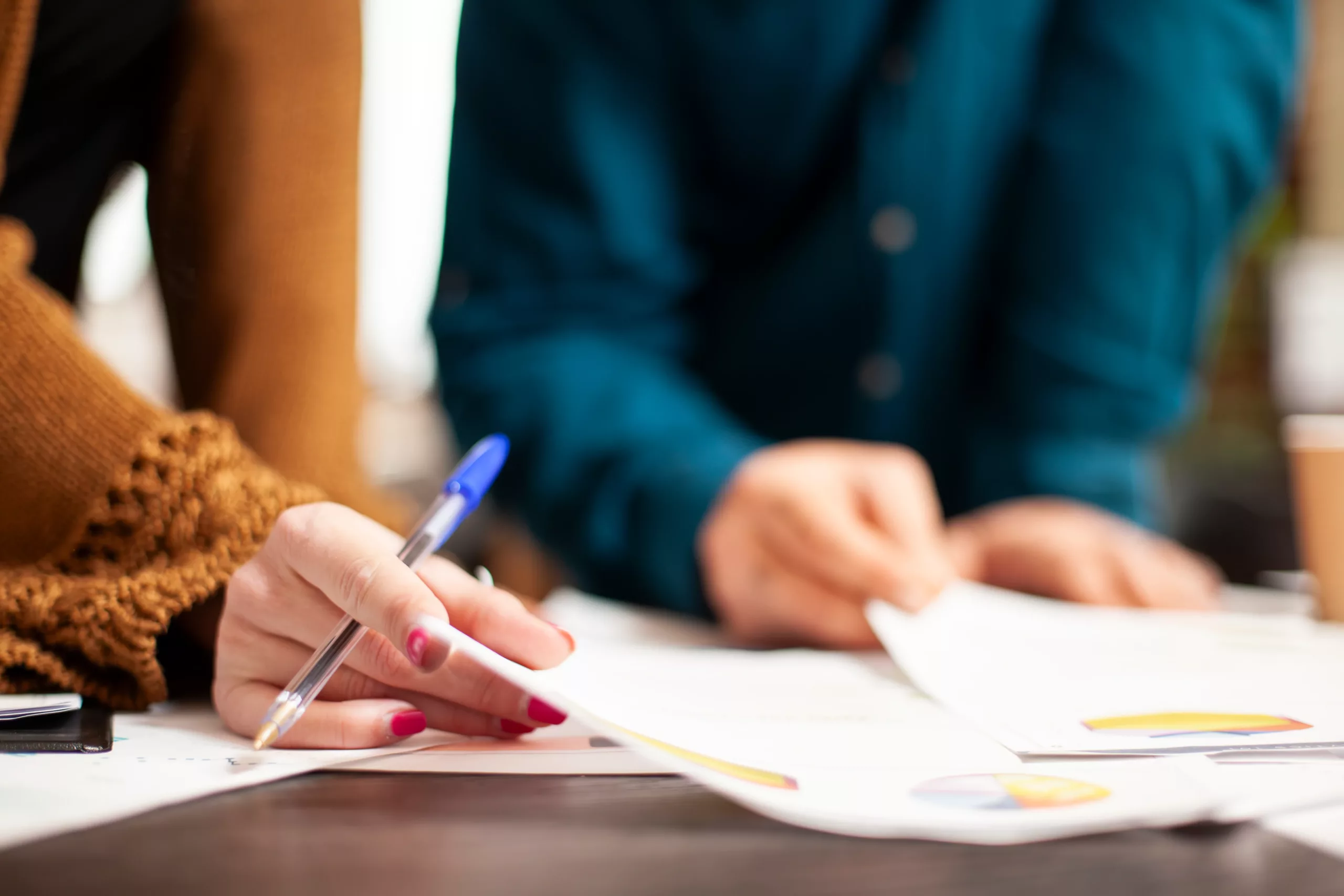 Two people reviewing documents with colorful charts and pen, collaborating on mortgage forbearance vs. loan modification concepts