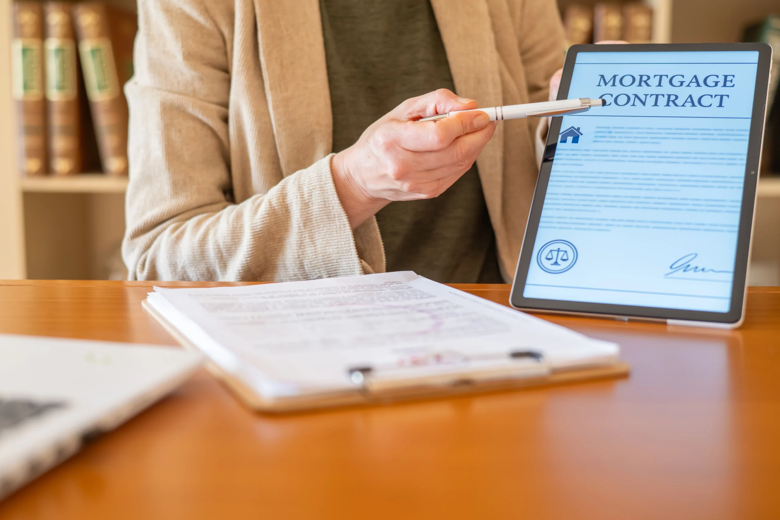 Person reviewing a digital mortgage contract on a tablet with documents and a pen, representing mortgage modification options that can lower payments or help homeowners catch up on missed payments.