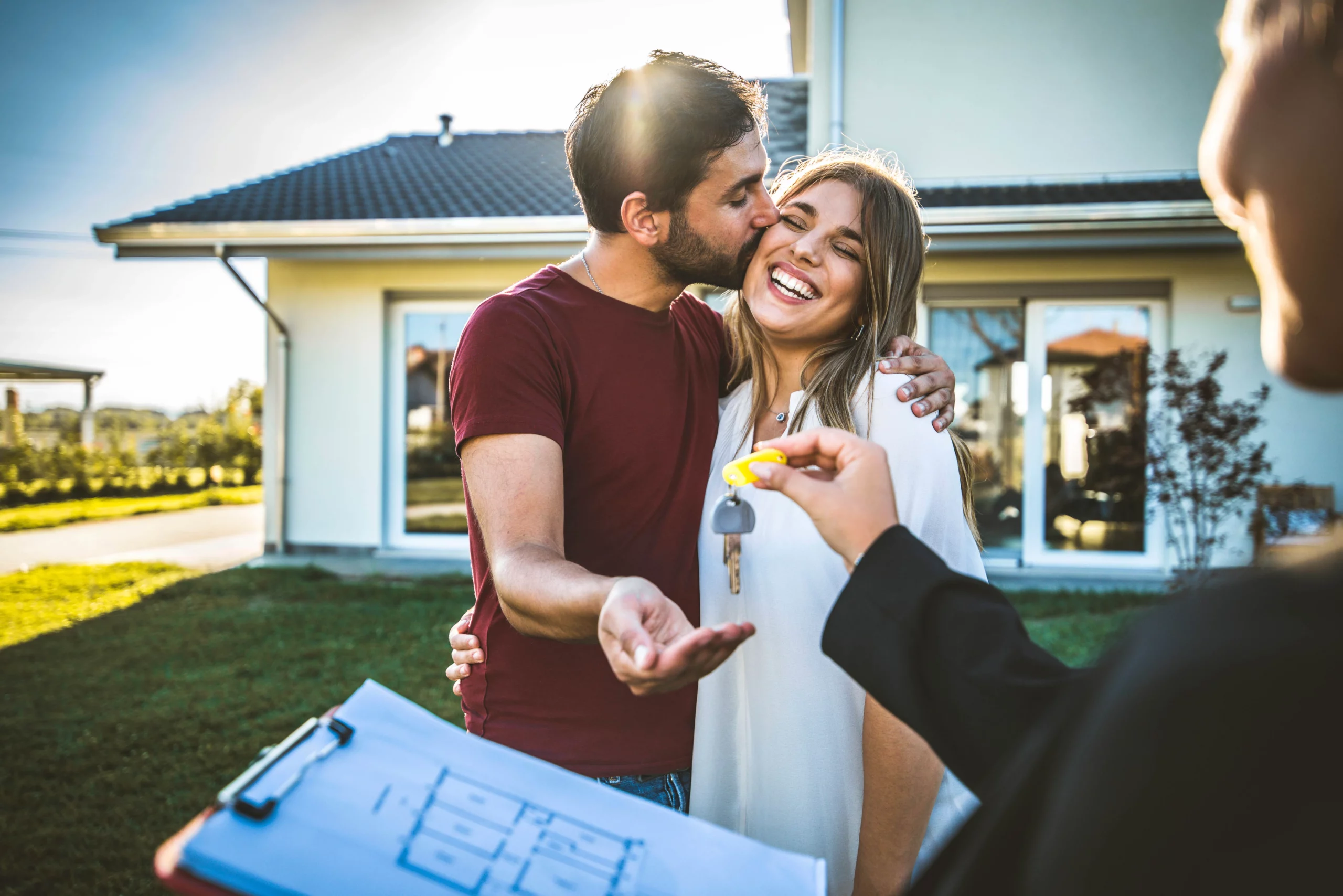 Happy couple receiving house keys in front of their new home, representing buying a house after Chapter 7 bankruptcy in Mississippi following the typical 2 to 4 year waiting period to qualify for a mortgage.