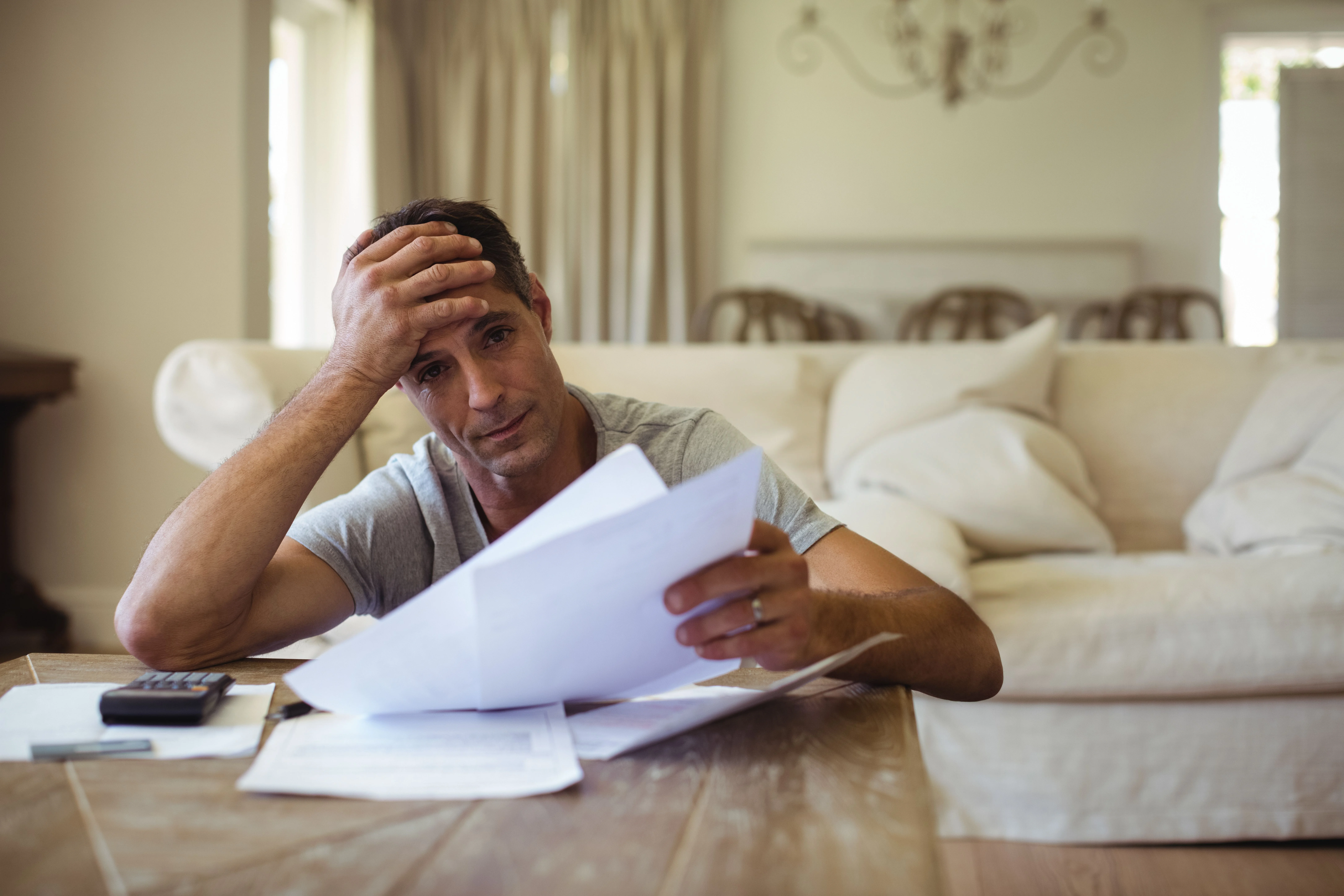 Stressed man reviewing bills with calculator and documents at home, representing concerns about tax refunds and whether they must be turned over in a Mississippi Chapter 7 bankruptcy